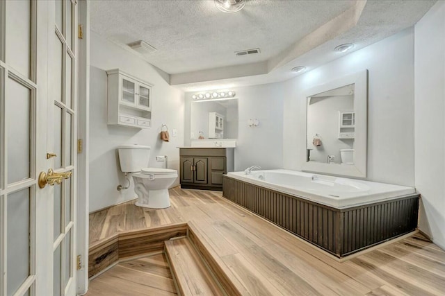 full bathroom featuring visible vents, toilet, wood finished floors, a textured ceiling, and vanity