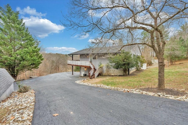 view of front facade featuring stairs, a front lawn, aphalt driveway, and a wooden deck