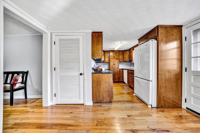 kitchen featuring crown molding, light hardwood / wood-style floors, and white appliances