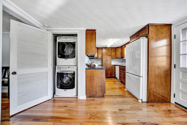kitchen with stacked washer / drying machine, light hardwood / wood-style floors, white appliances, and crown molding