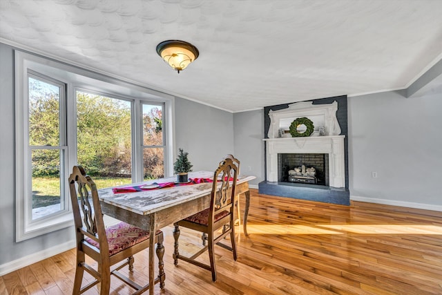 dining area with a large fireplace, light hardwood / wood-style floors, and crown molding