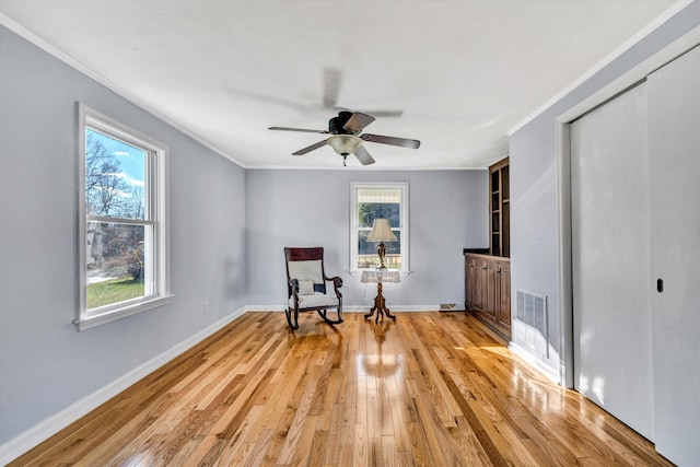 sitting room featuring ceiling fan, ornamental molding, a wealth of natural light, and light hardwood / wood-style flooring