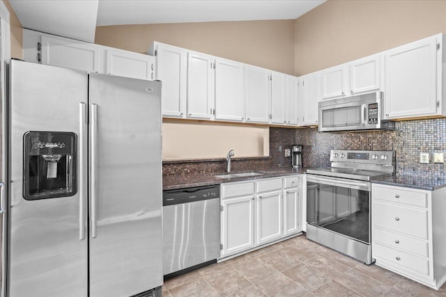 kitchen featuring white cabinets, appliances with stainless steel finishes, dark stone counters, decorative backsplash, and sink