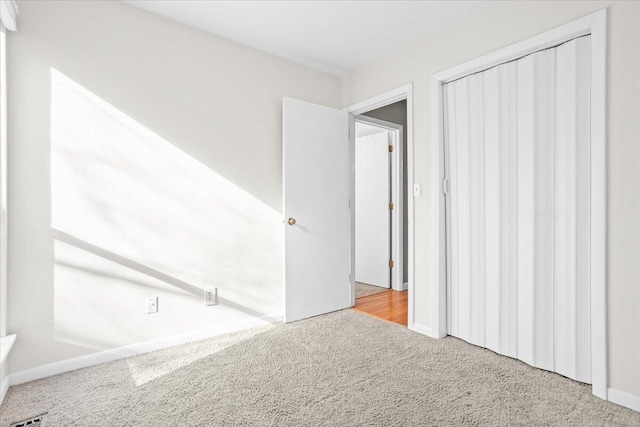 unfurnished bedroom featuring light carpet and a closet