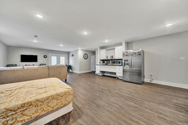 bedroom with dark wood-type flooring and stainless steel refrigerator with ice dispenser