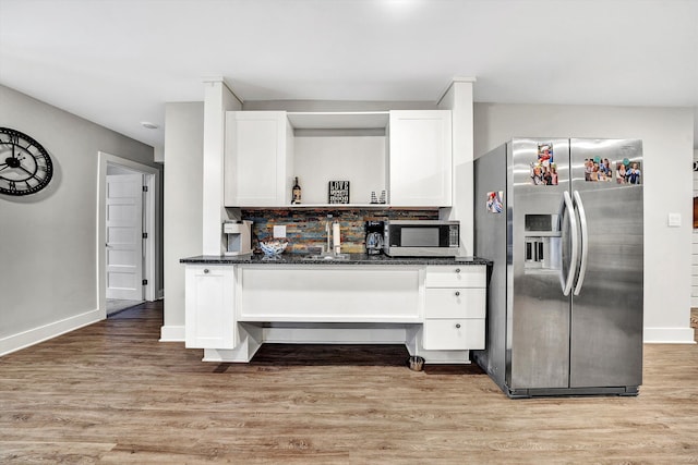 kitchen featuring white cabinets, stainless steel appliances, dark stone counters, and light hardwood / wood-style flooring