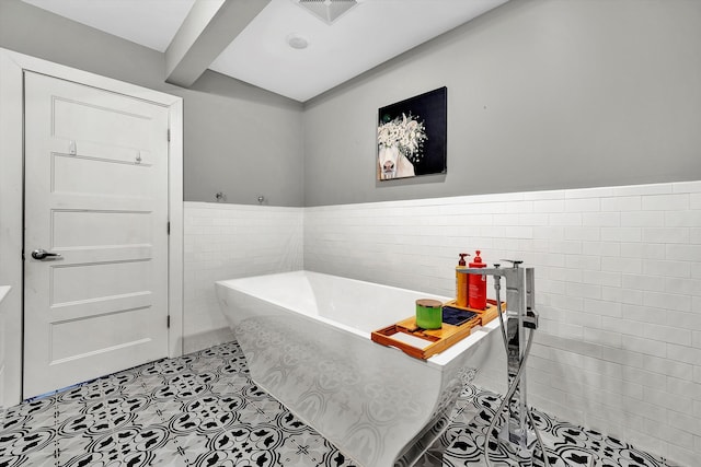 bathroom featuring a washtub, beam ceiling, and tile walls