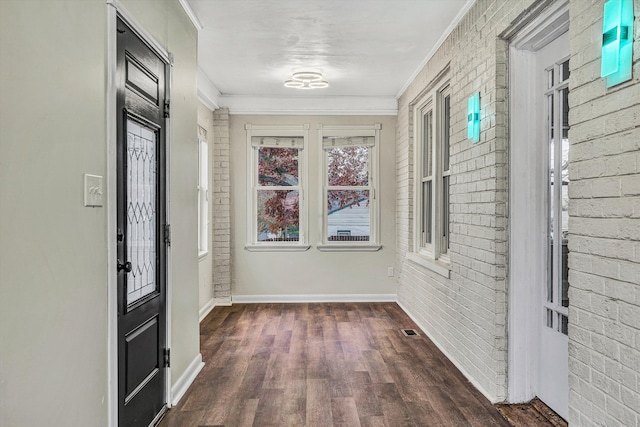 foyer entrance featuring dark hardwood / wood-style floors, ornamental molding, and brick wall