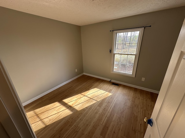 unfurnished room featuring light wood-type flooring and a textured ceiling