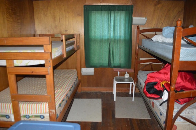 bedroom with wooden walls and dark hardwood / wood-style flooring