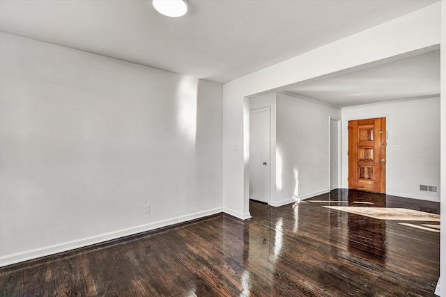 spare room featuring visible vents, baseboards, and wood finished floors