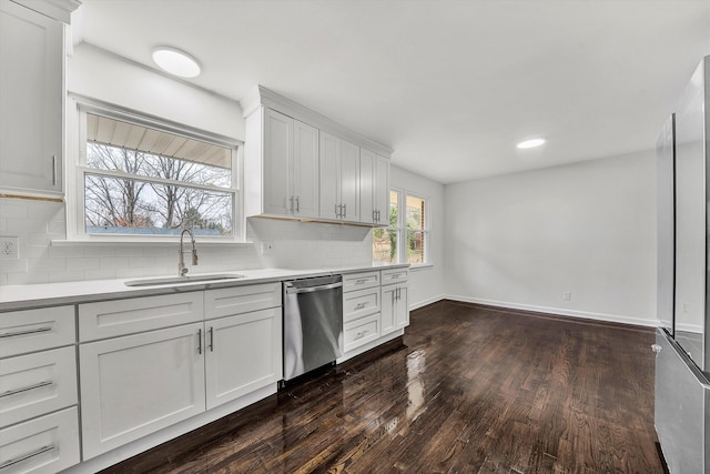 kitchen featuring dishwasher, light countertops, a sink, and white cabinets