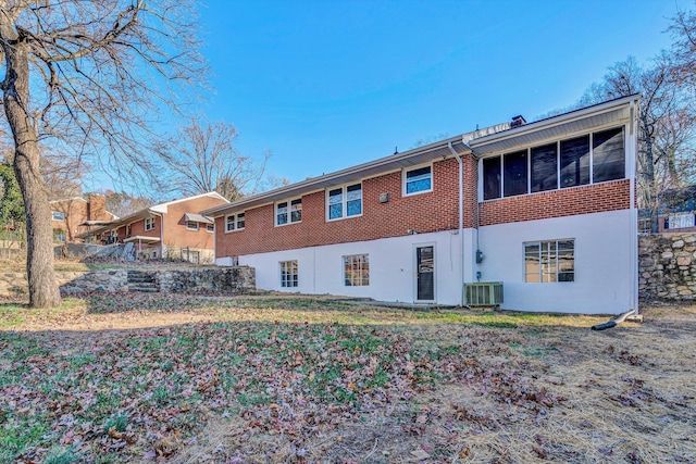 rear view of house featuring cooling unit, a sunroom, and brick siding