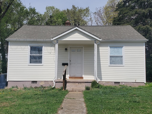 bungalow-style home with a front lawn, crawl space, and roof with shingles
