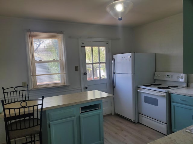 kitchen featuring light countertops, light wood finished floors, and white appliances