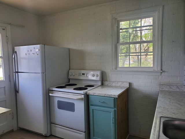 kitchen featuring brick wall, white appliances, light countertops, and blue cabinets