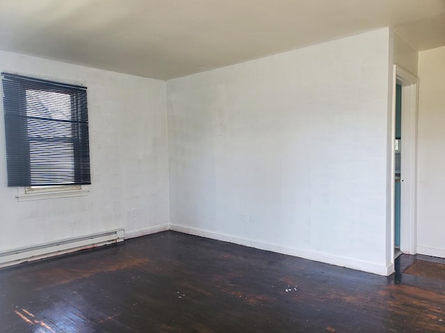 spare room featuring baseboards, a baseboard heating unit, and wood finished floors