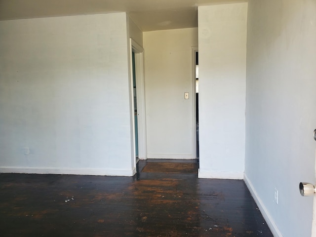 spare room featuring baseboards and dark wood finished floors