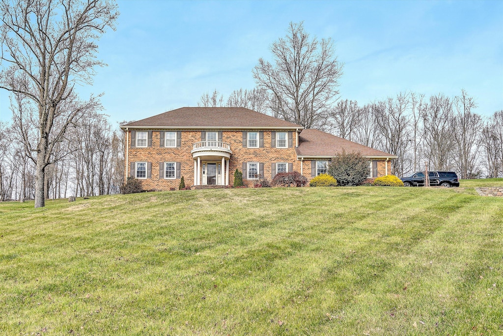 view of front of home with a balcony and a front yard