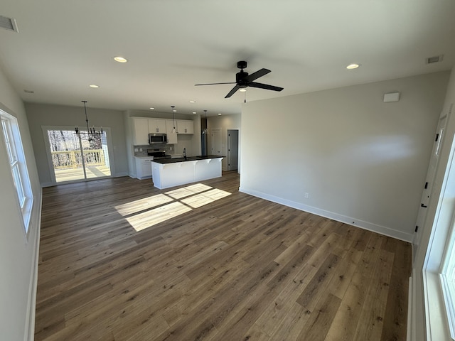 unfurnished living room with ceiling fan with notable chandelier, dark hardwood / wood-style flooring, and sink