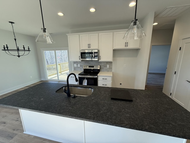 kitchen featuring white cabinetry, sink, stainless steel appliances, and a center island with sink