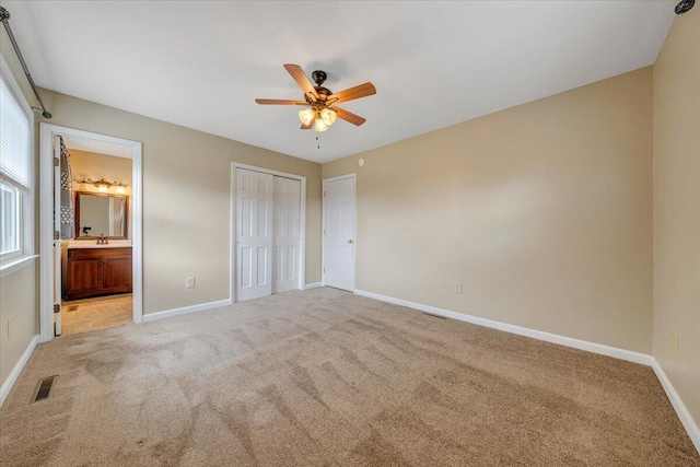 unfurnished bedroom featuring connected bathroom, ceiling fan, sink, and carpet