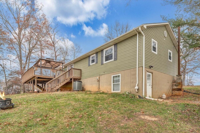 rear view of property featuring central AC unit, a fire pit, a deck, and a yard