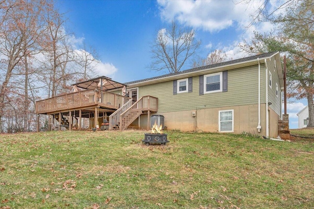 back of house featuring an outdoor fire pit, a yard, and a deck