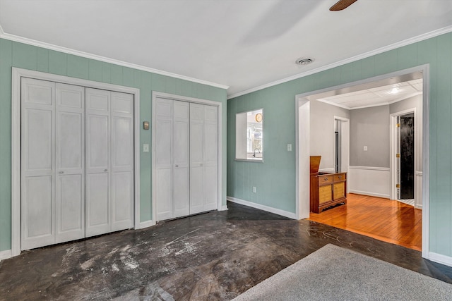 bedroom featuring ceiling fan, ornamental molding, and multiple closets