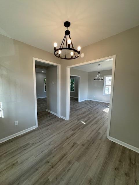 unfurnished dining area with an inviting chandelier and dark wood-type flooring