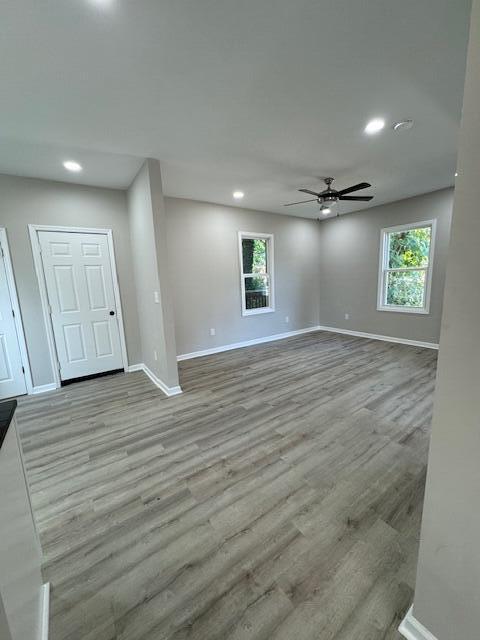 empty room featuring a healthy amount of sunlight, ceiling fan, and light hardwood / wood-style floors