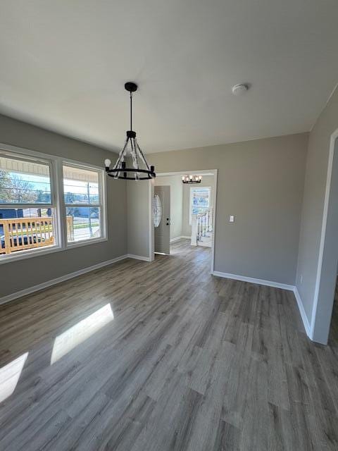 unfurnished dining area featuring wood-type flooring and an inviting chandelier