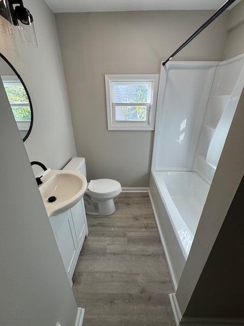 full bathroom with washtub / shower combination, hardwood / wood-style floors, vanity, and toilet