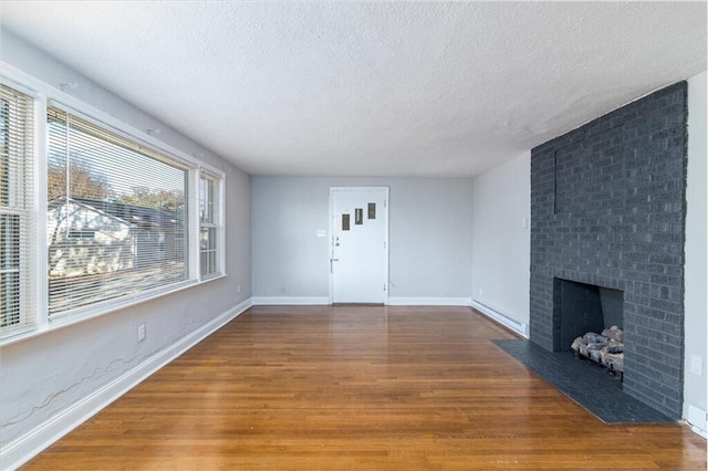 unfurnished living room with a textured ceiling, dark hardwood / wood-style floors, and a brick fireplace