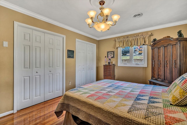 bedroom featuring a notable chandelier, two closets, and ornamental molding