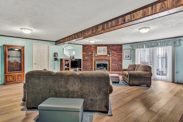 living room with a brick fireplace, crown molding, a textured ceiling, and light wood-type flooring