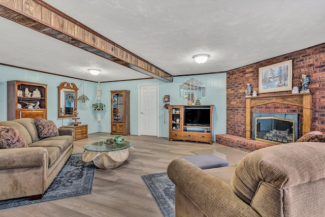 living room featuring a textured ceiling, a fireplace, ornamental molding, and wood-type flooring