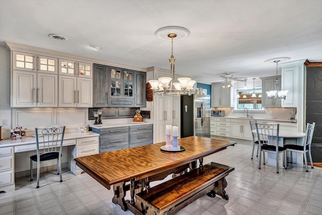 dining space featuring built in desk, sink, and ceiling fan with notable chandelier