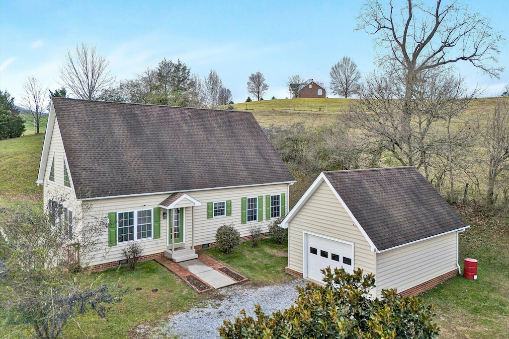 cape cod-style house featuring a front yard, a garage, and an outdoor structure