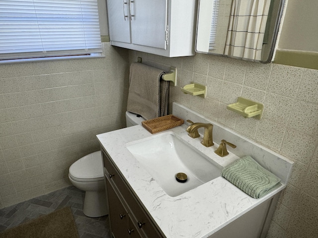 bathroom with vanity, toilet, and tile walls