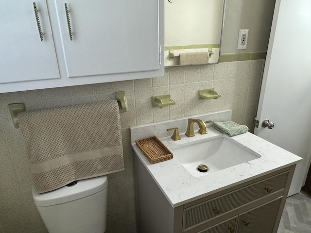 bathroom with vanity, tile walls, and toilet