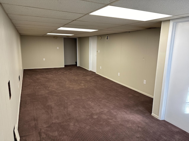 spare room with a drop ceiling and dark carpet