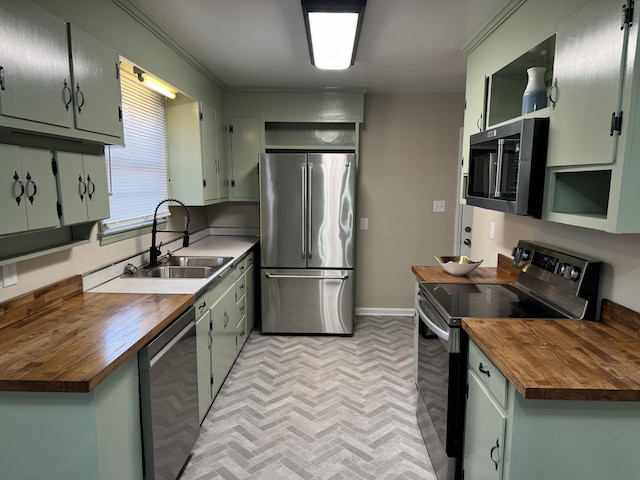 kitchen with butcher block countertops, sink, ornamental molding, and stainless steel appliances