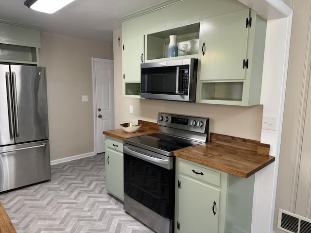 kitchen featuring butcher block countertops, green cabinets, and stainless steel appliances