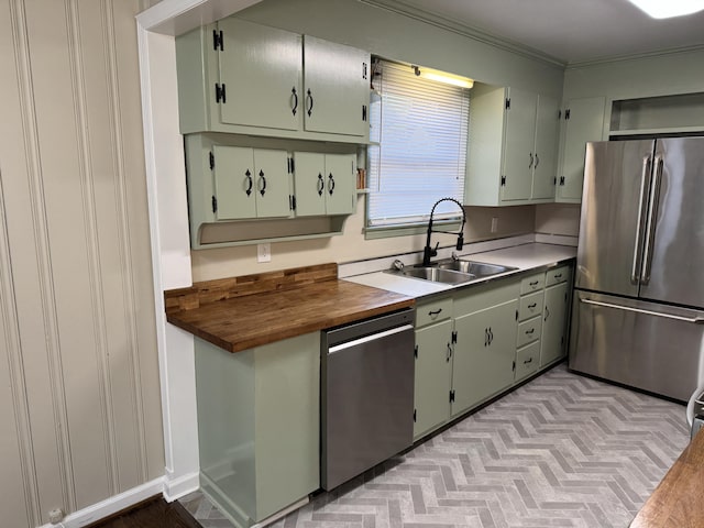 kitchen featuring butcher block counters, sink, light hardwood / wood-style floors, appliances with stainless steel finishes, and ornamental molding