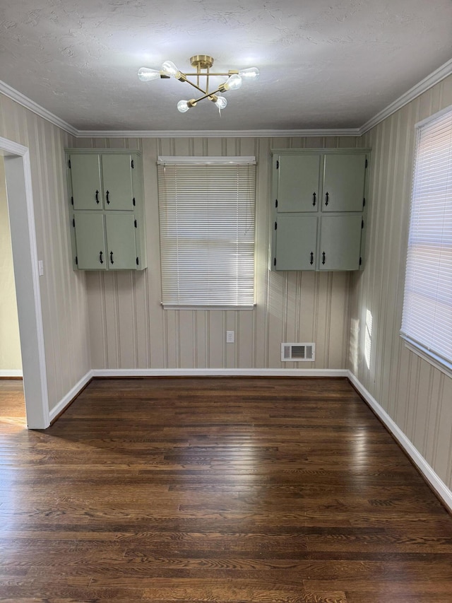 unfurnished room featuring ornamental molding, a textured ceiling, dark wood-type flooring, and a notable chandelier