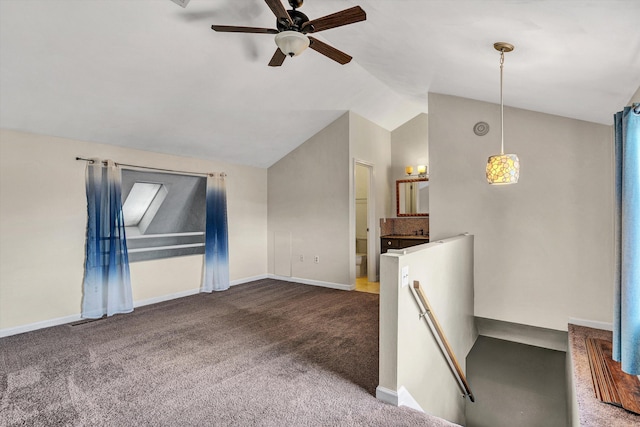 unfurnished living room featuring ceiling fan, vaulted ceiling, and dark colored carpet