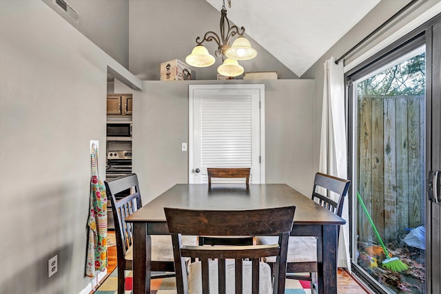 dining area featuring a chandelier, vaulted ceiling, and light wood-type flooring