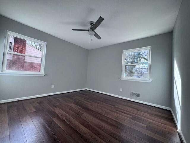 spare room featuring dark wood-type flooring, a wealth of natural light, and ceiling fan