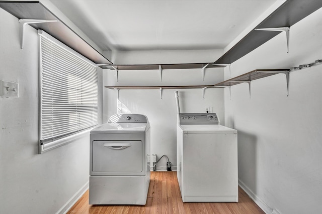 washroom with washing machine and clothes dryer and light hardwood / wood-style flooring